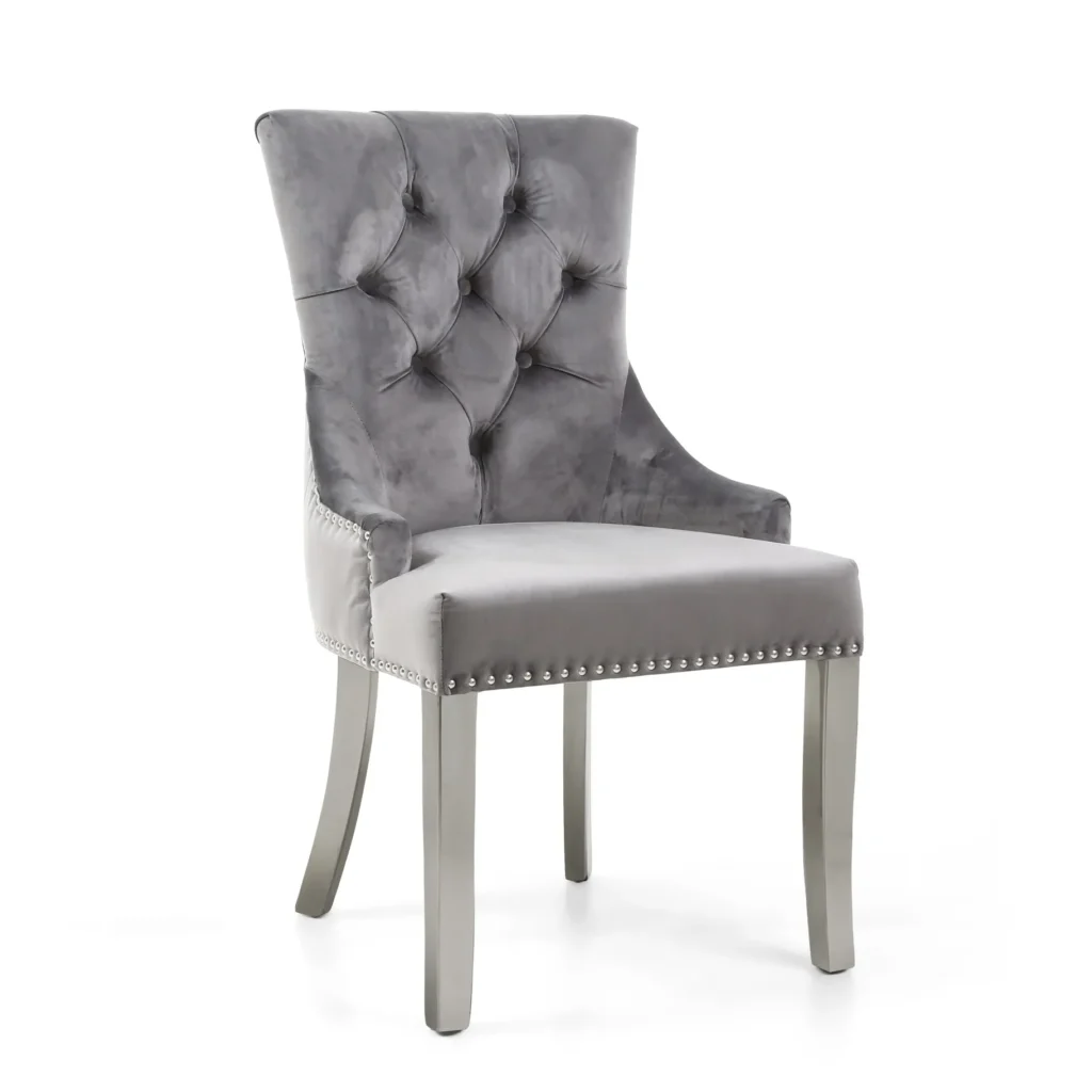 Elegant gray velvet chair with a high, tufted backrest and nailhead trim. The sleek wooden legs add a modern touch, conveying a sophisticated tone.