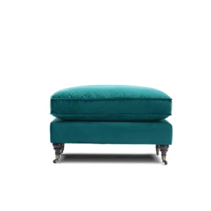 A teal velvet ottoman with a plush cushion sits on four dark wooden legs with small wheels, set against a white background. Elegant and modern design.