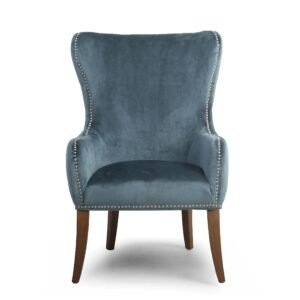 Elegant blue velvet armchair with high back, silver nailhead trim, and wooden legs. The chair conveys a sense of luxury and comfort.